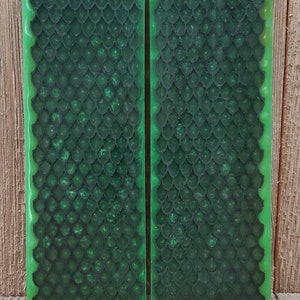 May include: Two rectangular, green resin pieces with a dark green, scale-like pattern. The edges are a bright green, and the background is a wooden surface. The pieces are side by side.