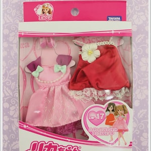 May include: A boxed doll clothing set with two outfits in pink and red. The pink dress has a bow and lace trim. The red cape-like dress has a white flower and lace trim. The packaging includes the text "Licca" and "TAKARA".