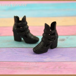 May include: A pair of black heeled ankle boots with cutouts and a textured finish. The boots have a chunky heel and a buckle detail.