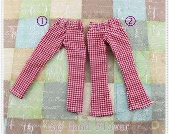 May include: Two pairs of red and white checked trousers. The trousers are flared and have a high waist. The trousers are labelled with numbers 1 and 2.