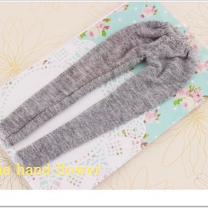 May include: Grey sweatpants with a ribbed texture. The sweatpants are laid out on a floral fabric background.