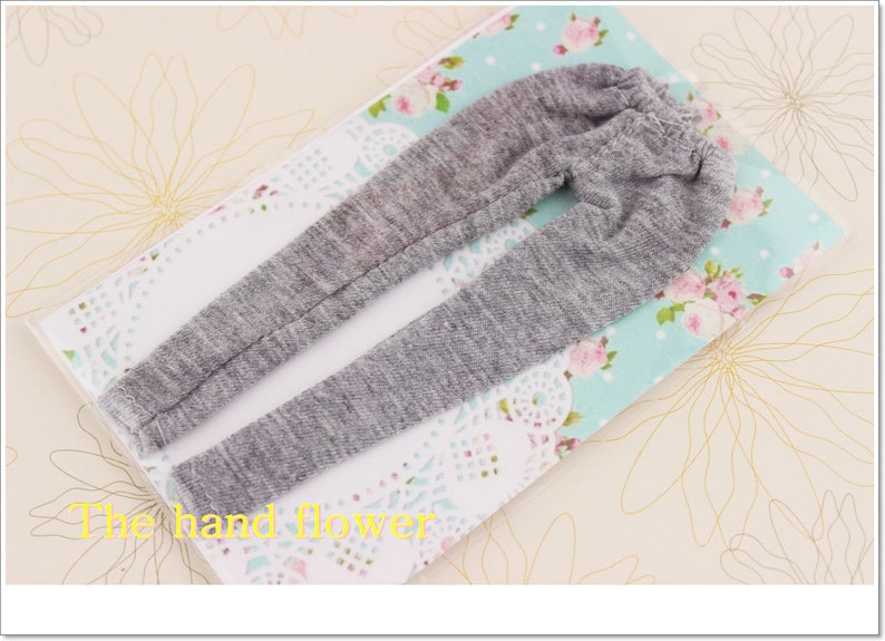 May include: Grey sweatpants with a ribbed texture. The sweatpants are laid out on a floral fabric background.