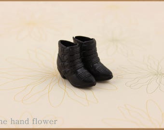 Puede incluir: Un par de botines negros con hebillas. Los botines están hechos de un material texturizado y tienen una punta puntiaguda.