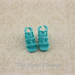 May include: A pair of turquoise blue sandals with a strappy design. The sandals have a closed toe and a high heel.
