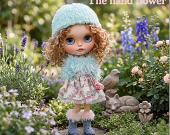 May include: A doll with curly hair, blue eyes, and a light blue hat and shawl, stands in a garden. The doll wears a floral dress and blue boots with pink trim. The text "The hand flower" is at the top of the image.