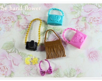 May include: A set of five miniature purses and a necklace. The purses are in various colors and styles, including a brown fringed purse, a pink purse with a heart-shaped design, and a blue purse with a heart-shaped design that says "Oh! I Love You". The necklace is pink and has a bow.