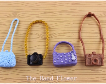 May include: Four miniature purses and cameras, including a light blue quilted purse, a purple purse with silver accents, a black camera with a gold chain, and a brown camera with a brown strap.