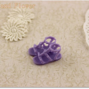 May include: A pair of lavender-colored sandals with a gladiator-style design. The sandals have multiple straps and buckles.