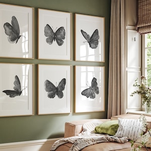 Puede incluir: Seis impresiones de mariposas en blanco y negro enmarcadas en una pared verde. Las impresiones están dispuestas en dos filas de tres. Cada impresión presenta un diseño de mariposa diferente.