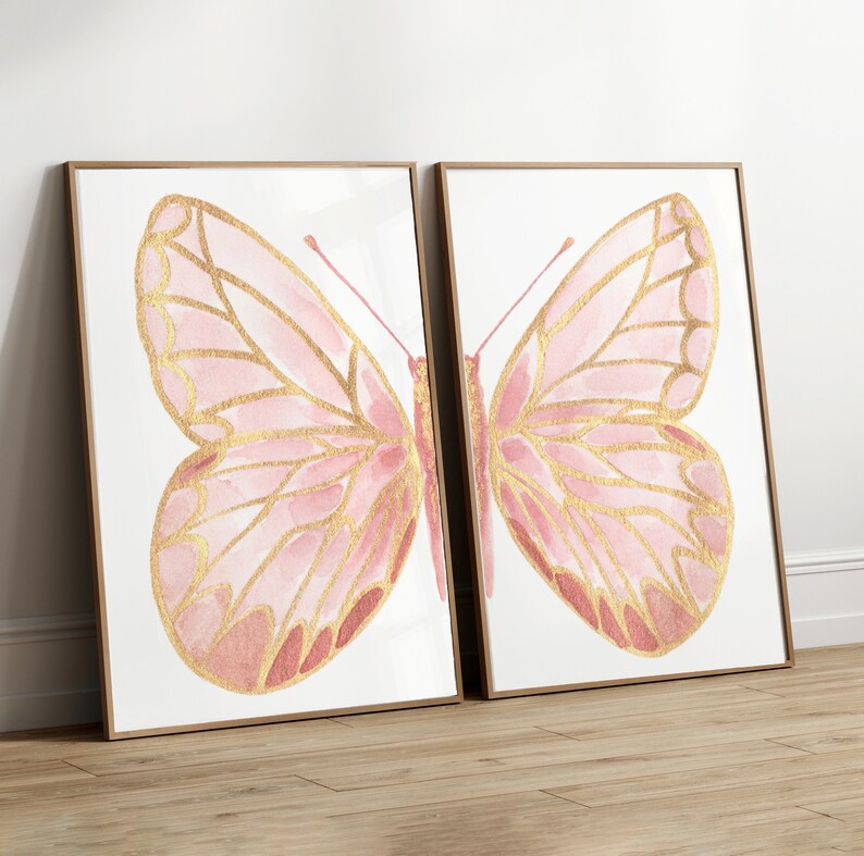 May include: Two framed prints of pink and gold butterflies. The butterflies are painted in a watercolor style with gold accents.