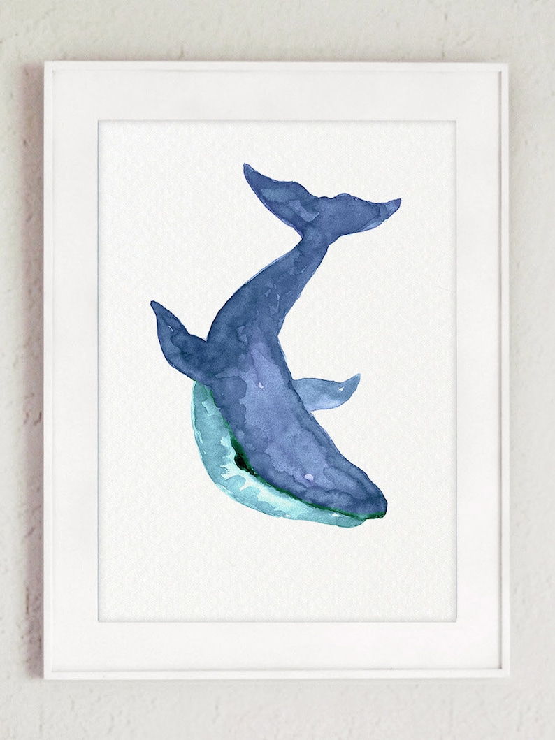 Puede incluir: Una pintura de acuarela de una ballena azul sobre un fondo blanco. La ballena est&aacute; mirando al espectador y tiene la boca abierta. La pintura est&aacute; enmarcada en un marco blanco.