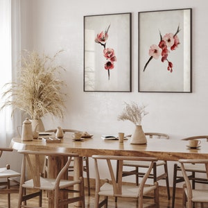 May include: Two framed watercolor paintings of pink and red flowers on a branch, hanging on a white wall above a wooden dining table with chairs.
