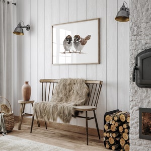 May include: A watercolor painting of two sparrows perched on a branch. The painting is framed and hanging on a white wall. The wall is made of wood planks. There is a wooden bench with a fur throw on it in front of the painting.