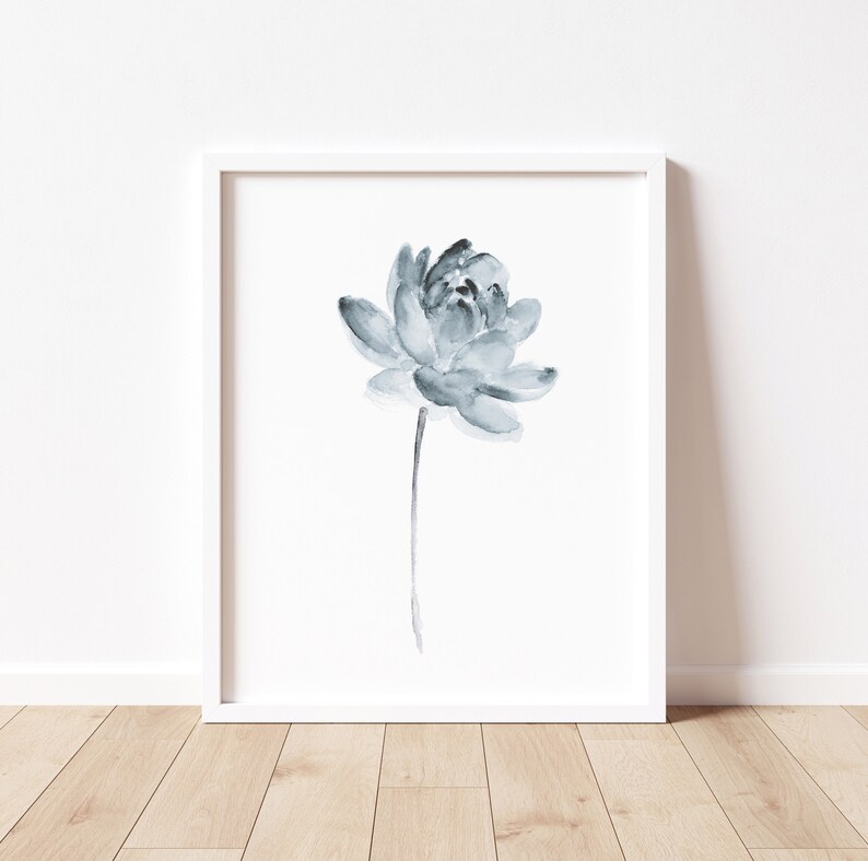 K&ouml;nnte beinhalten: Ein gerahmtes Aquarellbild einer einzelnen blauen Blume mit einem d&uuml;nnen Stiel. Die Blume befindet sich in der Mitte des wei&szlig;en Passepartouts und der Rahmen ist wei&szlig;.