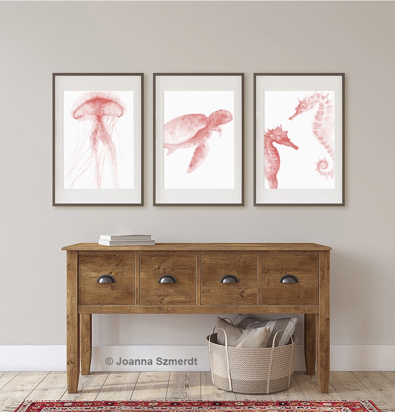 May include: Three framed watercolor prints of sea creatures in shades of pink. The prints feature a jellyfish, a sea turtle, and a seahorse.