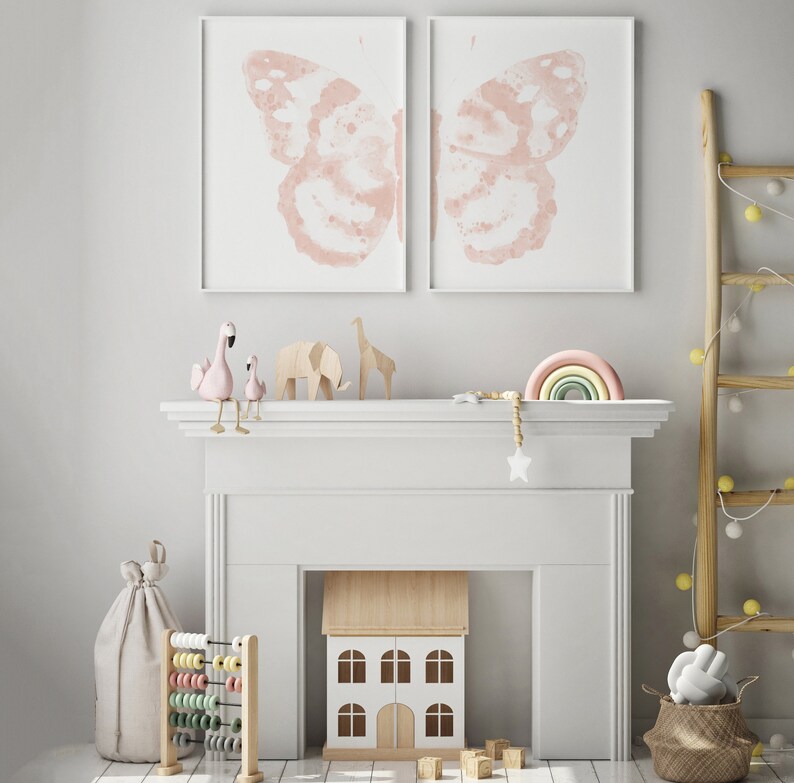 May include: A white fireplace mantel with a toy house, a wooden abacus, and a rainbow-colored wooden arch. Two pink flamingo figurines are perched on the mantel, and two butterfly prints hang above.