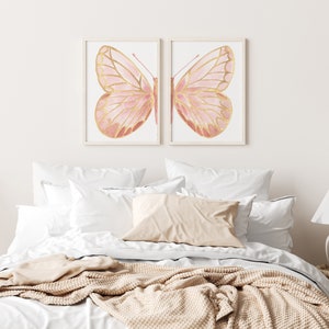 May include: Two framed prints of pink and gold butterflies with intricate details. The butterflies are set against a white background.
