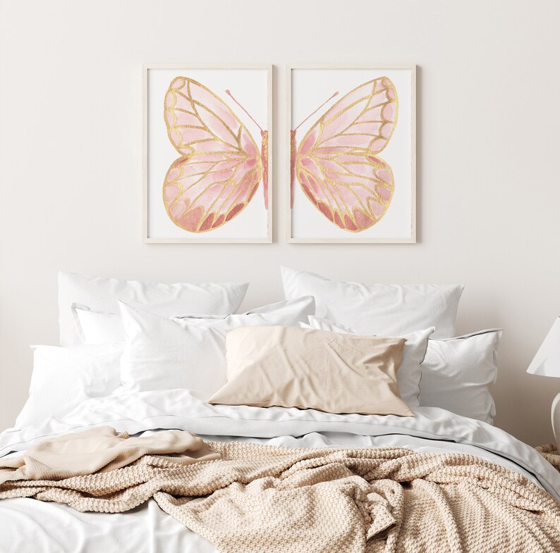 May include: Two framed prints of pink and gold butterflies with intricate details. The butterflies are set against a white background.