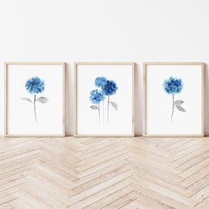 May include: Three watercolor prints of blue hydrangeas on a white background. Each print is framed in a light wood frame.