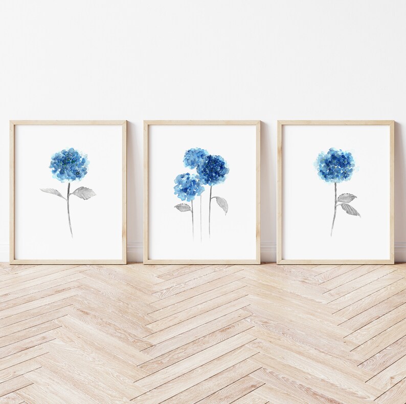 May include: Three watercolor prints of blue hydrangeas on a white background. Each print is framed in a light wood frame.