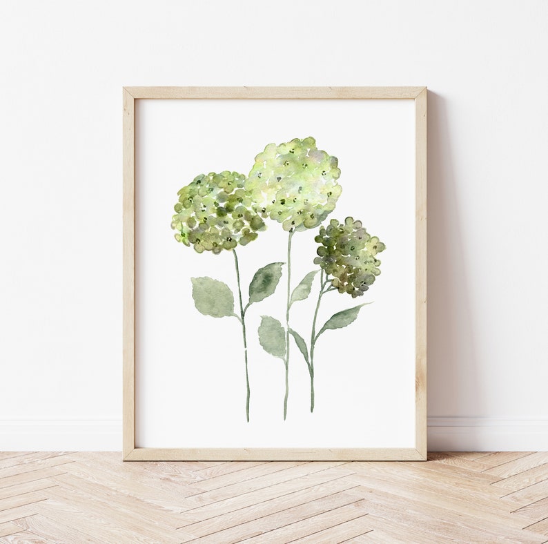 May include: A framed watercolor painting of three green hydrangeas with white centers. The flowers are on stems with green leaves against a white background.