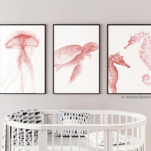 May include: Three framed watercolor prints of sea creatures in a coral pink color. The prints feature a jellyfish, a sea turtle, and two seahorses.