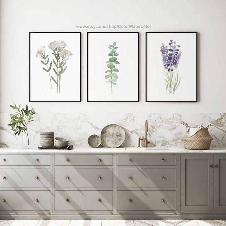 May include: Three framed watercolor prints of botanical illustrations. The prints feature a sprig of white flowers, a sprig of eucalyptus leaves, and a sprig of lavender flowers.
