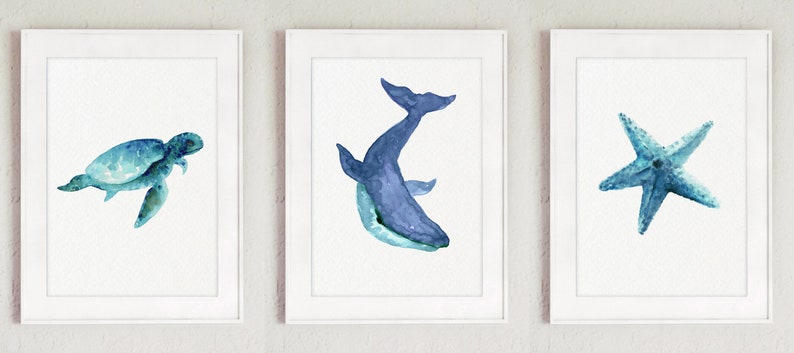 Puede incluir: Tres acuarelas en marcos blancos. Las pinturas representan una tortuga marina azul, una ballena azul y una estrella de mar azul.