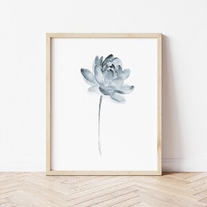 K&ouml;nnte beinhalten: Ein gerahmtes Aquarellbild einer einzelnen blauen Blume mit einem langen Stiel. Die Blume befindet sich in der Mitte des wei&szlig;en Hintergrunds.