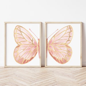 May include: Two framed prints of pink and gold butterflies. The butterflies are watercolor illustrations with a delicate, feminine style.
