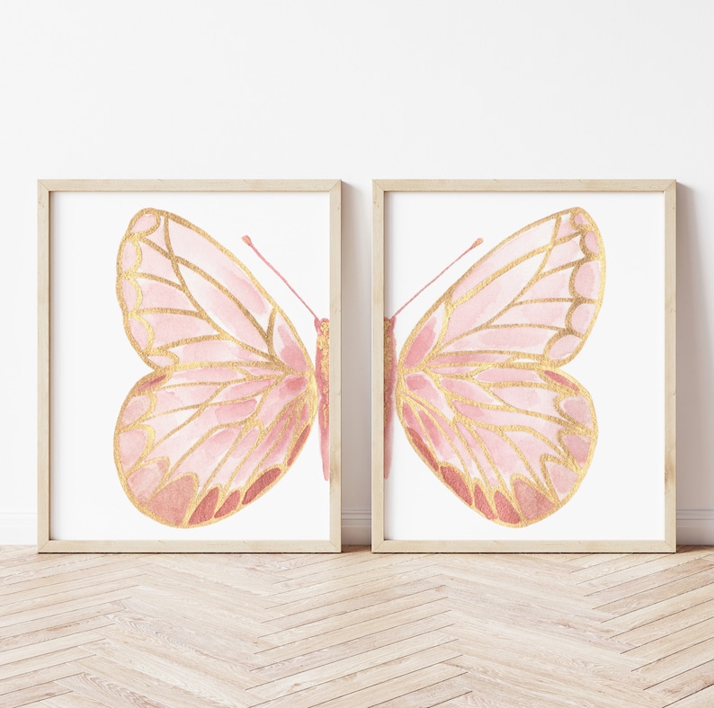 May include: Two framed prints of pink and gold butterflies. The butterflies are watercolor illustrations with a delicate, feminine style.