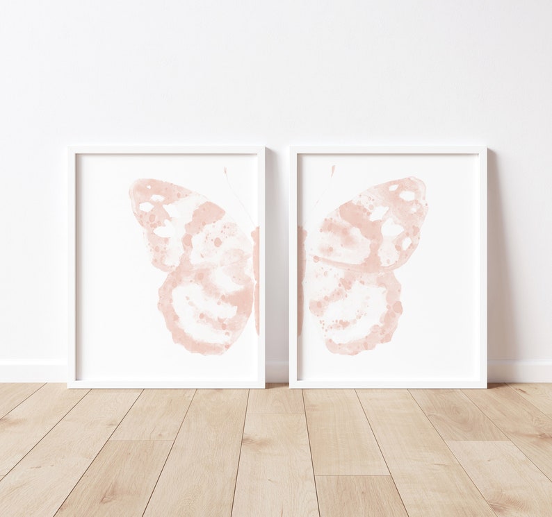 May include: Two white framed prints with a pink watercolor butterfly design. Each print features a single butterfly wing.