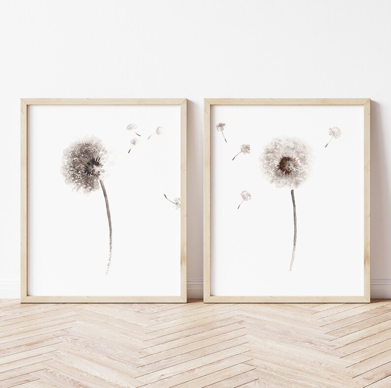 May include: Two framed prints of black and white watercolor dandelion illustrations. The dandelions are in various stages of seed dispersal. The prints are in simple wooden frames.