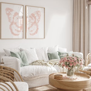May include: A white couch with pillows and a throw blanket in a living room setting. A vase of pink flowers sits on a wooden coffee table with a woven basket.