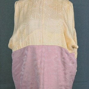 May include: A vintage kimono with a yellow and pink patterned design. The kimono is made of silk and has a traditional Japanese style.