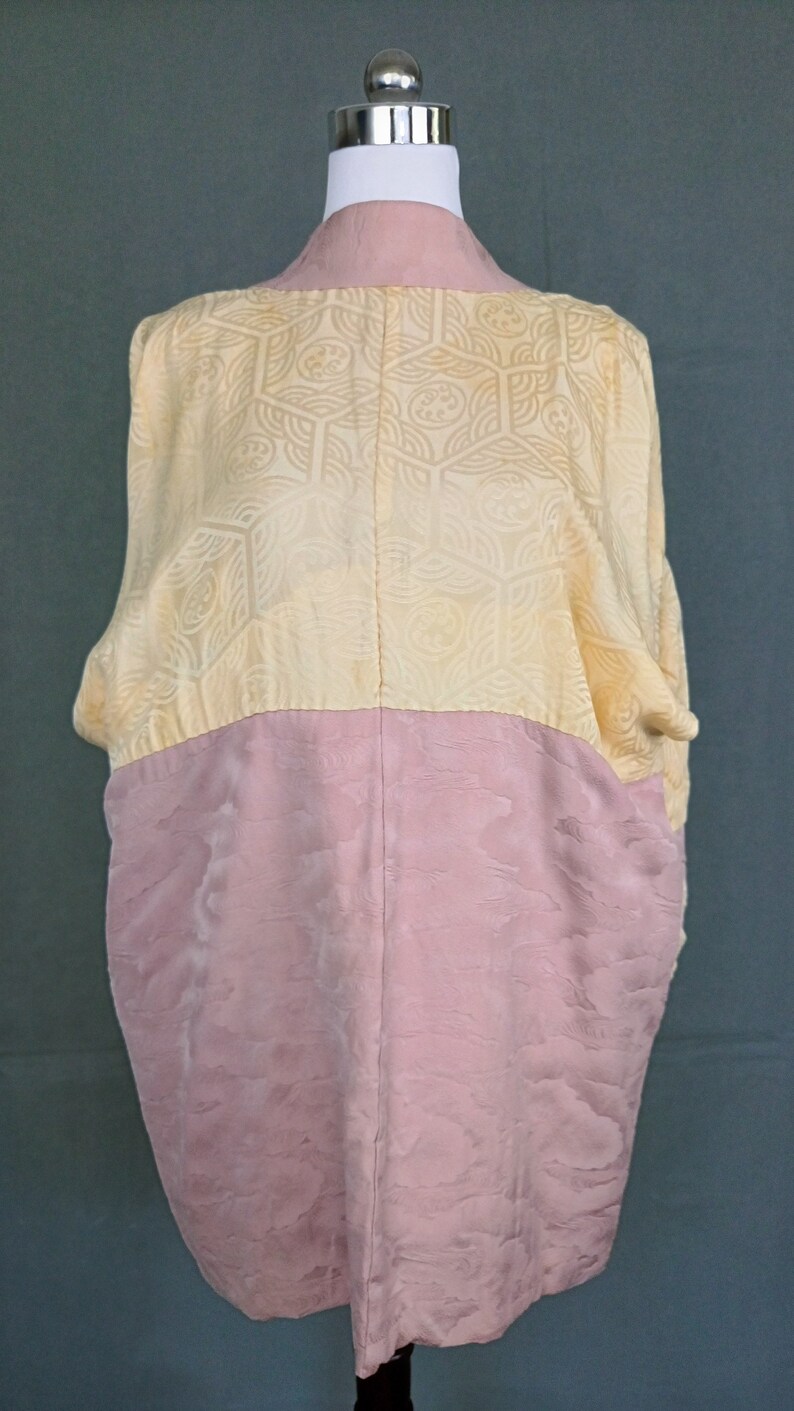 May include: A vintage kimono with a yellow and pink patterned design. The kimono is made of silk and has a traditional Japanese style.