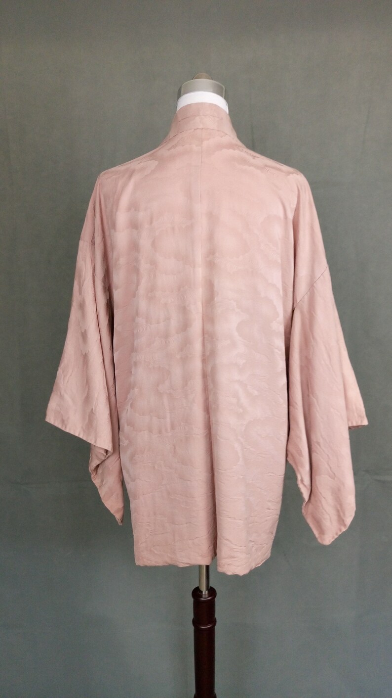 May include: A pale pink kimono with a cloud pattern. The kimono is made of a soft, silky fabric and has a relaxed fit.