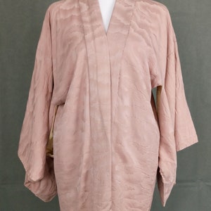 May include: A pale pink kimono with a subtle cloud pattern. The kimono is made of a soft, silky fabric and has a relaxed fit.