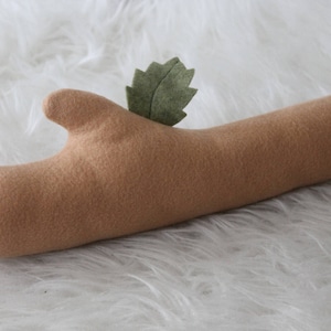 May include: A brown felt log with a green felt leaf on top. The log is a prop for newborn photography.
