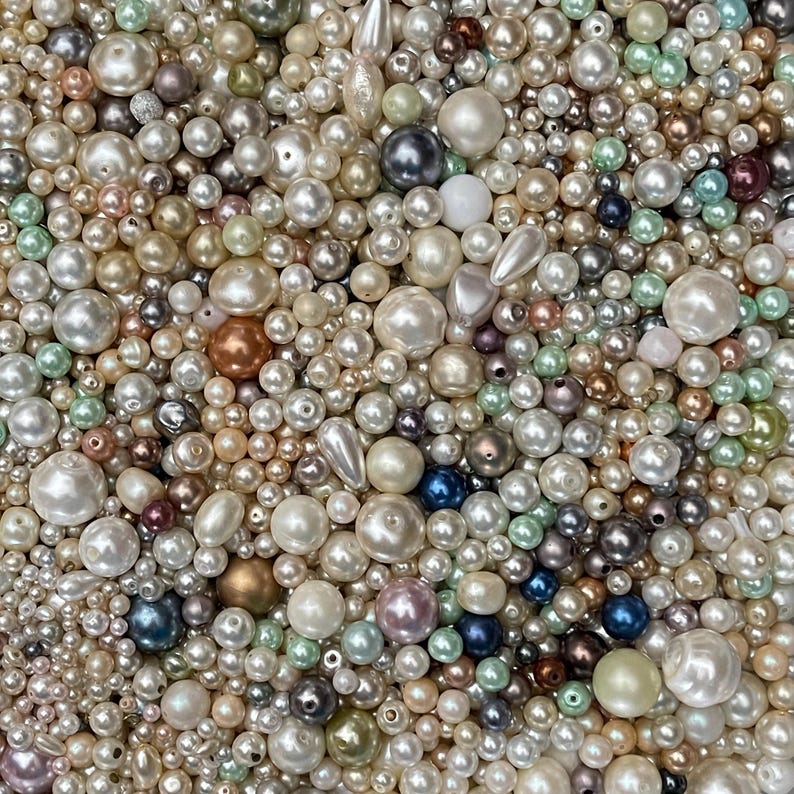 May include: A large collection of loose beads in various sizes and shapes, featuring a mix of white, cream, metallic gold, bronze, silver, soft pink, light blue, and mint green colors with smooth, lustrous, and pearlescent finishes.