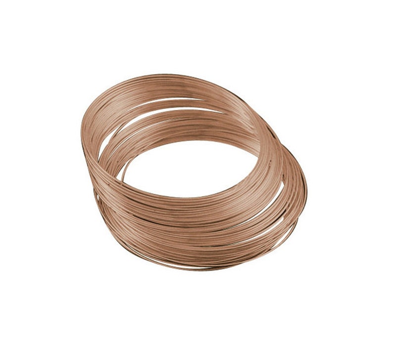Puede incluir: Una bobina de alambre color cobre, enrollada en forma circular. El alambre parece delgado y flexible, con una superficie lisa. La imagen est&aacute; sobre un fondo blanco liso, resaltando la forma del alambre.