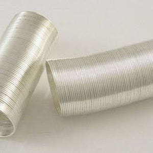 Può includere: Due bobine di filo color argento, ciascuna avvolta a forma di cilindro. Il filo è sottile e lucido, e le bobine sono lunghe circa 25 cm.