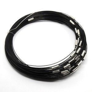 May include: A coil of black cord with multiple strands, featuring silver-colored metal clasps. The cord is tightly wound, suggesting a jewelry-making or crafting supply. The image is set against a plain white background.
