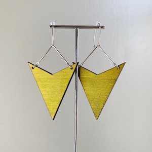 May include: A pair of gold-colored wooden earrings shaped like triangles with silver hooks.