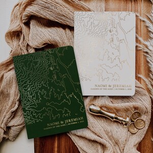 May include: Two rectangular wedding invitation cards featuring gold topographic map line art. One card is dark green with gold text, the other is white with gold text. Both read Naomi & Jeremiah, Garden of the Gods, October 1, 2024. Includes a metal wax seal stamp.