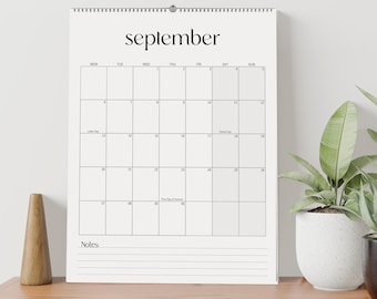 May include: A white wall calendar for the month of September with a black wire spiral binding at the top. The calendar features a grid layout for the days of the month, with the word September printed in a black serif font at the top.