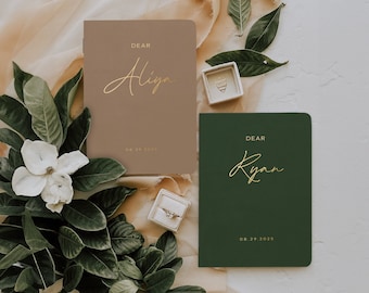 May include: Two small, hardcover journals with gold lettering. The journal on the left is brown and says "Dear Aliya 08.19.2023". The journal on the right is green and says "Dear Ryan 08.29.2023".