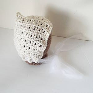 May include: A white crocheted bonnet with a white tulle veil attached.