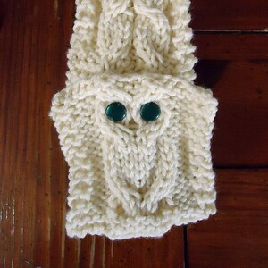 May include: White knitted owl hand warmer with green button eyes.