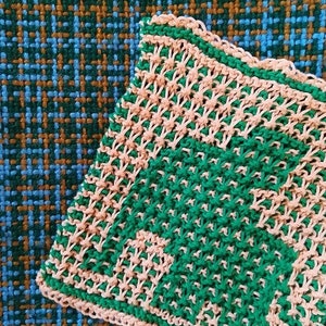 Puede incluir: Primer plano de un pa&ntilde;o de cocina tejido con un patr&oacute;n de cuadros verde y rosa. El pa&ntilde;o de cocina est&aacute; hecho con un punto sencillo y tiene una superficie ligeramente texturizada.